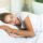 Woman sleeping on her side with her cheek pressed into a white pillow