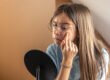 Young woman checking her skin for breakouts in a hand mirror