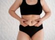 Woman gently pinching a small area of lower belly fat