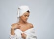 Woman in a robe checking the skin on her chest and shoulder before dark spots on chest treatment