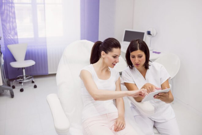 Filler Consultation Records Review Photo Provider reviewing a tablet with a smiling patient during a dermal filler consultation in Chicago