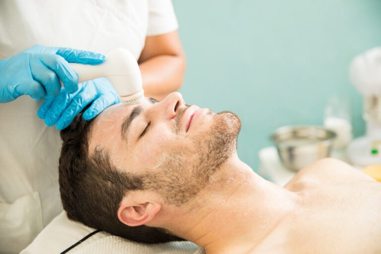 Microdermabrasion for Men With Beards Photo Man with light stubble enjoying a professional facial exfoliation treatment at a med spa