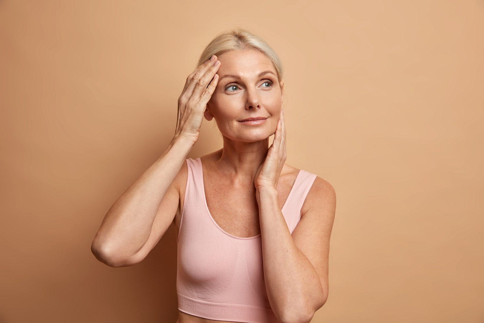 Confident mature woman touching her smooth cheeks after Sculptra collagen treatment for menopause volume loss in Chicago