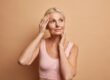Confident woman touching her smooth, fuller cheeks after Sculptra treatment for facial volume loss after weight loss