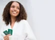 Smiling woman holding a VI Peel treatment kit, comparing VI Peel and IPL for pigmentation and sun spots in Chicago