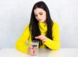 Woman taking a daily tablet with a small glass of water at home in the morning